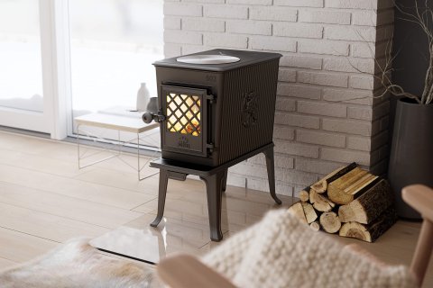 Jøtul F 602, a small black wood stove in front of a white fire wall.