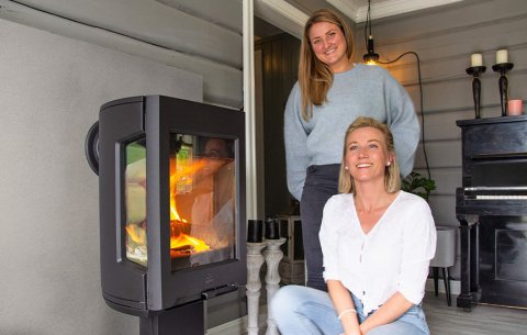 Two ladies sit in front of the Jøtul F 167 stove in a gray living room.