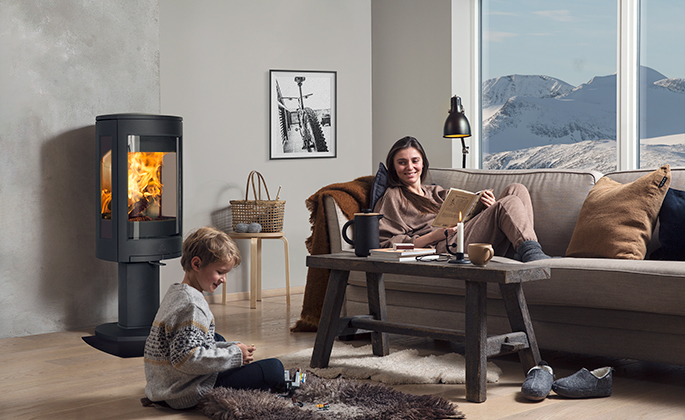 A mother and her son sitting by the fire from their Jøtul F 373 Advance wood burning stove