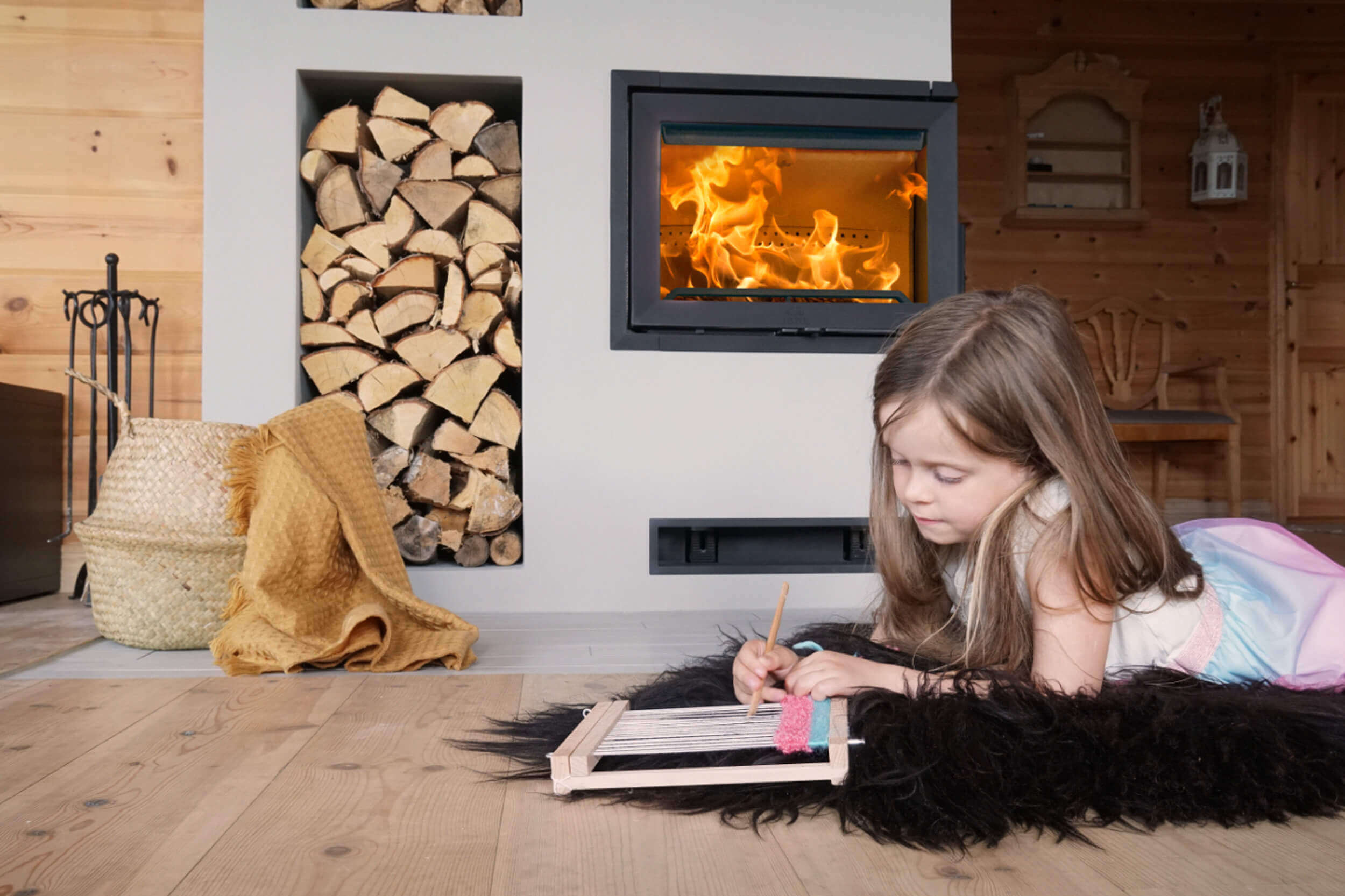 Girl sitting in front of the fireplace Jøtul I 520 FR in a Norwegian cabin.