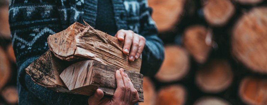 Man with cardigan holding firewood