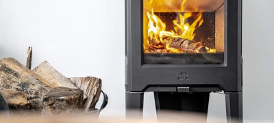 Jøtul F 163 black wood stove with logs on the side and white wall at the back 