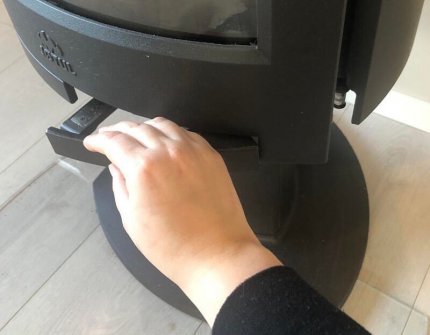 The hand which open the door carefully of the wood stove 