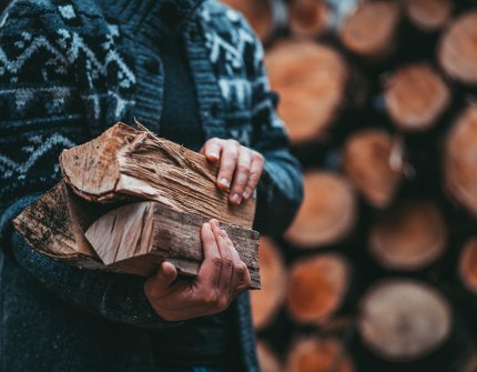 Man in cardigan holding on firewood