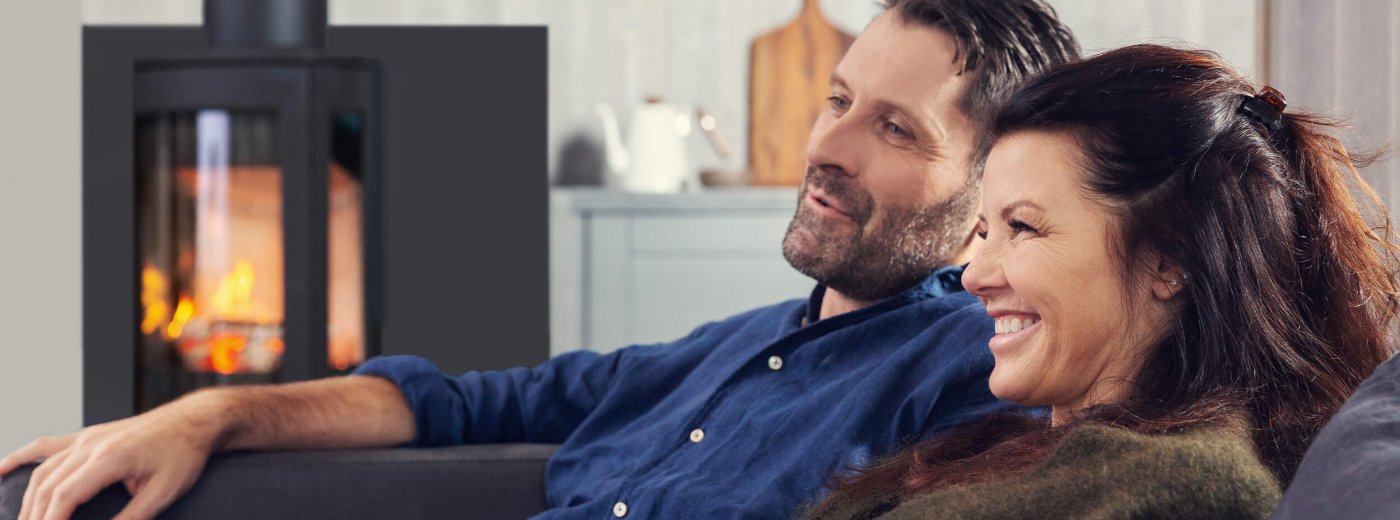 Man and woman sitting in front of the wood stove Jøtul F 373 Advance in the living room 