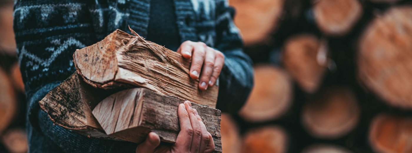 Man with cardigan holding firewood