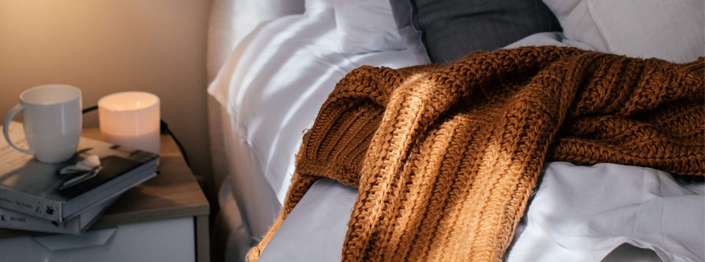 Cosy blanket and coffee cup on the bed