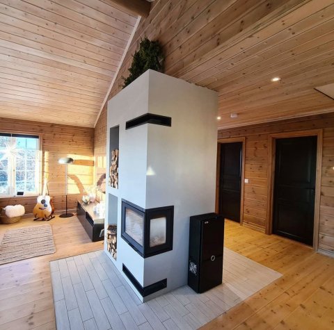 White surround with a black wood insert called Jøtul I 520 FR in a Norwegian cabin.