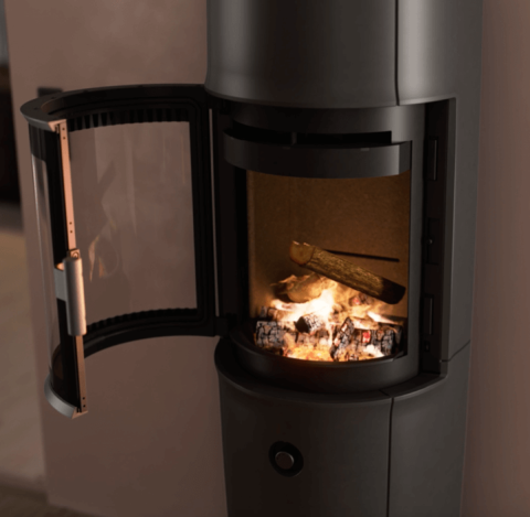 Modern room with large black Jøtul F 174 wood stove with open door, powder-purple walls